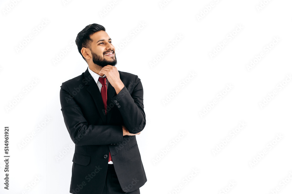 Positive elegant influential arabian or indian man in formal suit, standing over isolated white background, looking away, thinking, planning, dreaming, smiles happily. Copy-space for your presentation Positive elegant influential arabian or indian man in formal suit, standing over isolated white background, looking away, thinking, planning, dreaming, smiles happily. Copy-space for your presentation