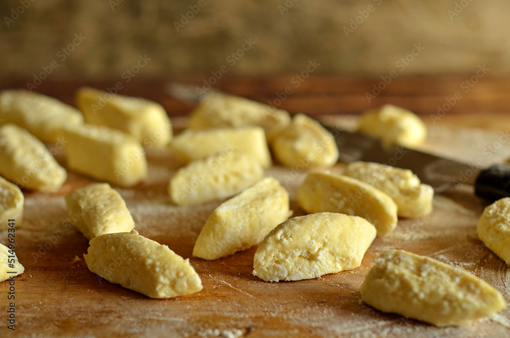 Fototapeta premium Uncooked lazy dumplings sprinkled with flour on a wooden board