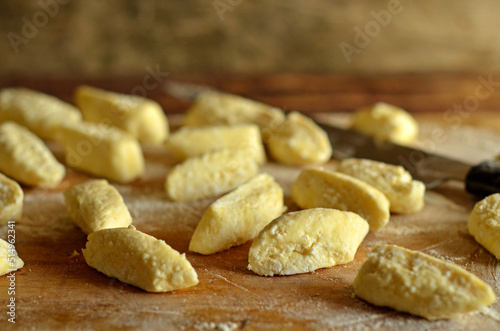 Uncooked lazy dumplings sprinkled with flour on a wooden board