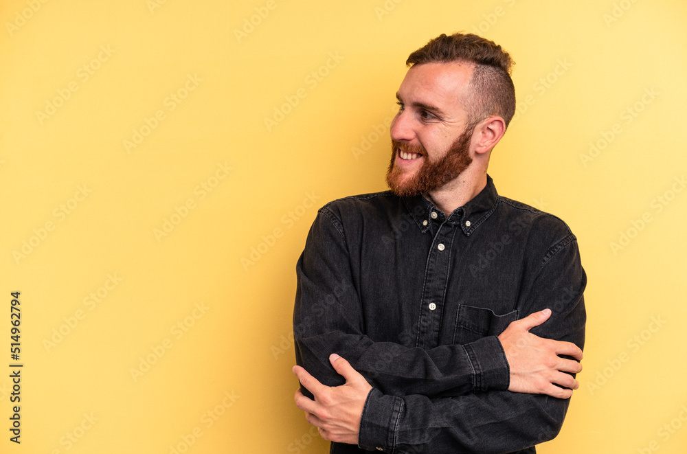 Obraz premium Young caucasian man isolated on yellow background smiling confident with crossed arms.
