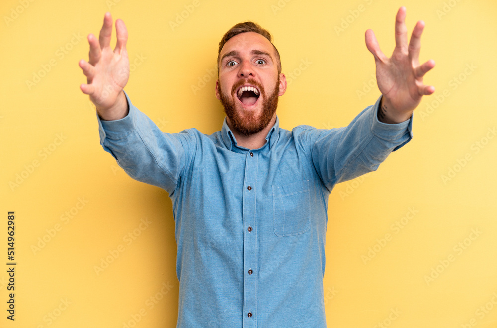 Young caucasian man isolated on yellow background celebrating a victory or success, he is surprised and shocked. Young caucasian man isolated on yellow background celebrating a victory or success, he is surprised and shocked.
