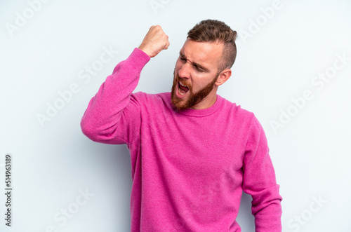 Young caucasian man isolated on blue background celebrating a victory, passion and enthusiasm, happy expression.