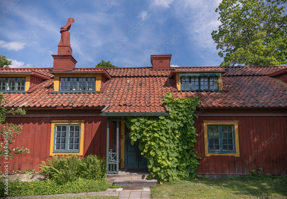 Old wood 1800s red house with dorms, tin chimney and entrance covered in flower leaves, a summer day in Stockholm Old wood 1800s red house with dorms, tin chimney and entrance covered in flower leaves, a summer day in Stockholm