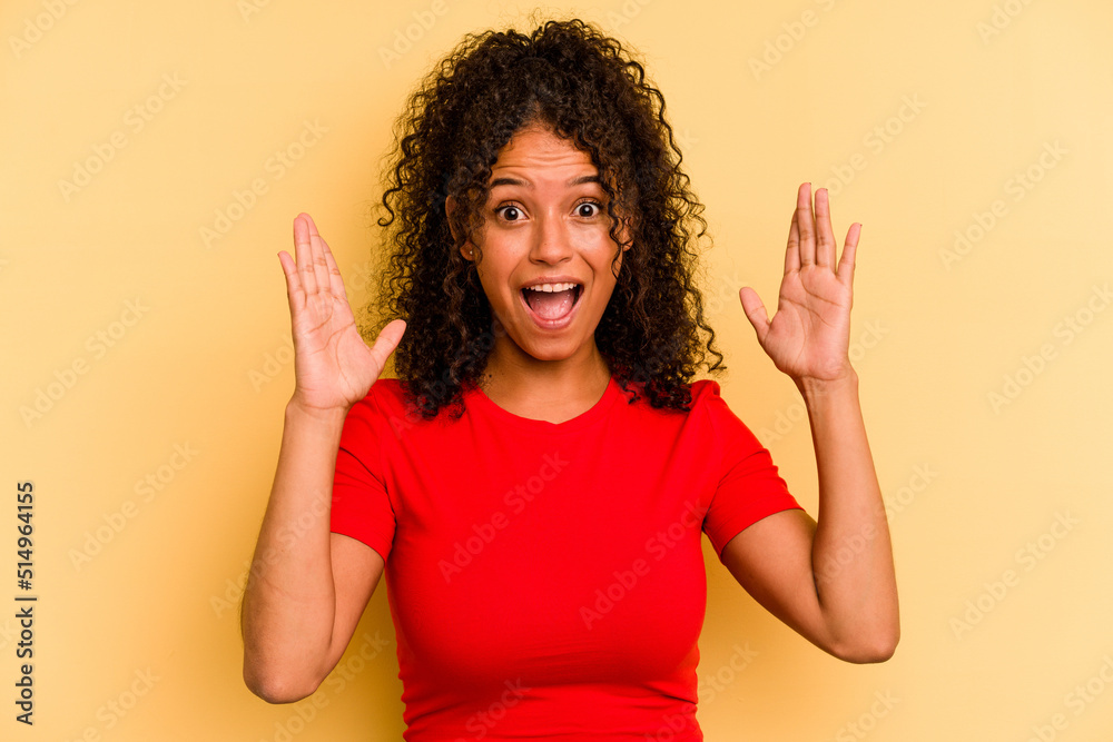 Young Brazilian woman isolated on yellow background celebrating a victory or success, he is surprised and shocked. Young Brazilian woman isolated on yellow background celebrating a victory or success, he is surprised and shocked.