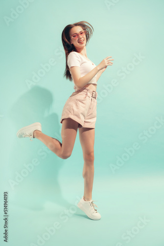 Fototapeta Naklejka Na Ścianę i Meble -  Excited young beautiful girl with long hair posing isolated on light blue color background. Concept of beauty, art, fashion, emotions, youth