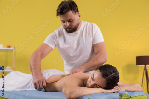 Therapist man at his massage room doing back massage with his elbows practicing revitalising massage while client laying on the massage table