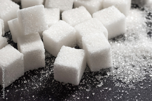 Cubes of refined sugar on a dark table close-up