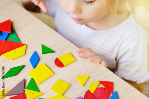 cute child, girl 3 years old plays with colored wooden geometric figures, counts details, concept of development of creativity, fine motor skills, patience perseverance, children's entertainment