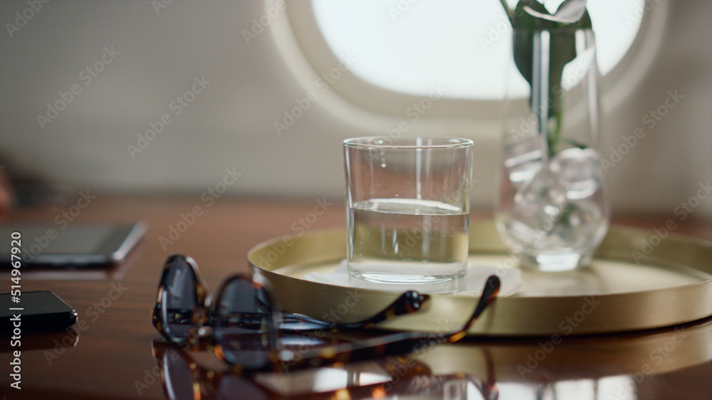Hand putting water glass on table closeup. Airplane passenger resting on trip