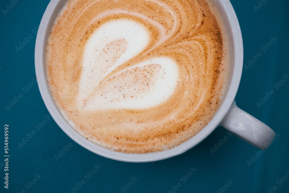 Cappuccino with latte art in the shape of a heart on a shabby blue surface. Close up Cappuccino with latte art in the shape of a heart on a shabby blue surface. Close up