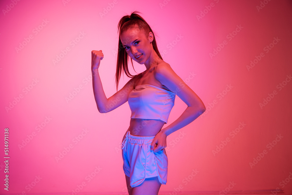 Young beautiful girl with long hair posing isolated on magenta color background in neon light. Concept of beauty, art, fashion, emotions, youth Young beautiful girl with long hair posing isolated on magenta color background in neon light. Concept of beauty, art, fashion, emotions, youth