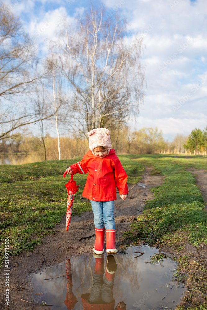 Child plays with umbrella after the rain in red rubber boots and a raincoat. Child plays with umbrella after the rain in red rubber boots and a raincoat.