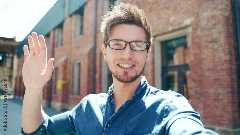 POV young man communicates online by video call on the front camera of a smartphone outdoors. outside. smart phone webcam view screen. Happy student guy waves his hand and speaks point of view