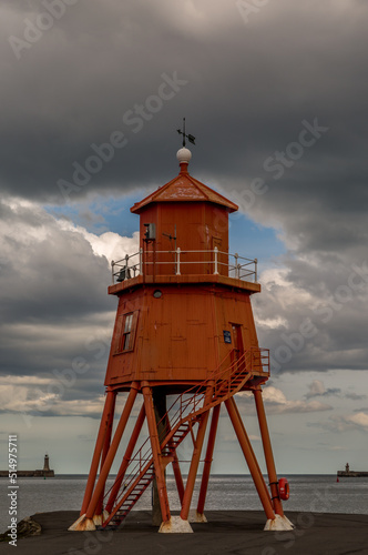 The old, red, wooden Herd Groyne Lighthouse in South Shields, stands out against the cloudy sky 