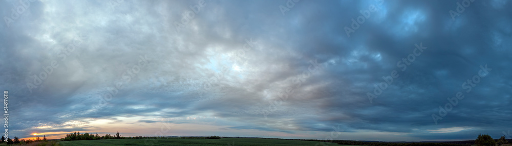 Panorama of dawn fire in the sky above the natural pasture. Golden red clouds just before sunrise. Picturesque landscape at sunrise. Beauty in nature