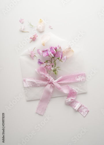 A message for Valentine's Day. A message with pink flowers and an envelope with a pretty ribbon on a white background © Olga
