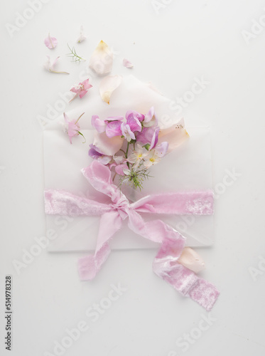 Romantic letter. A message with pink flowers and an envelope with a pretty ribbon on a white background © Olga