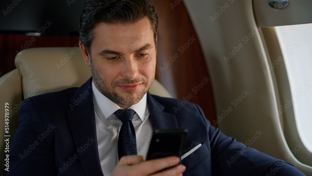 Successful man looking smartphone at airplane window. Delighted businessman rest Successful man looking smartphone at airplane window. Delighted businessman rest