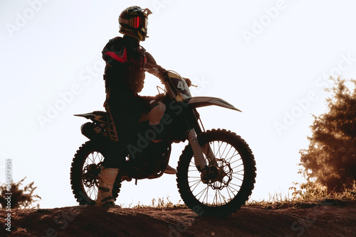 Fototapeta Man's silhouette, motocross rider on motorbike admiring the sunset at summer day evening, outdoors