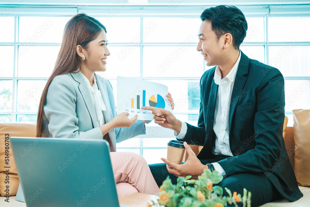 Business couple sitting together with a cup of coffee and checking work on sofa near the window background. Business couple sitting together with a cup of coffee and checking work on sofa near the window background.