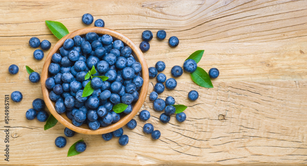 Top view of blueberries in wooden bowl on rustic table