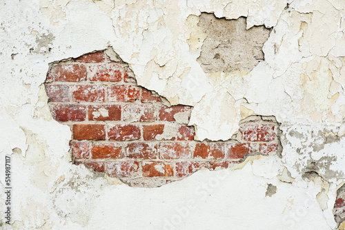 Texture of an old brick wall with damaged plaster and cracked paint.