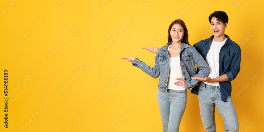 Two Young good looking asian couple using isolated on yellow background presenting to copy space