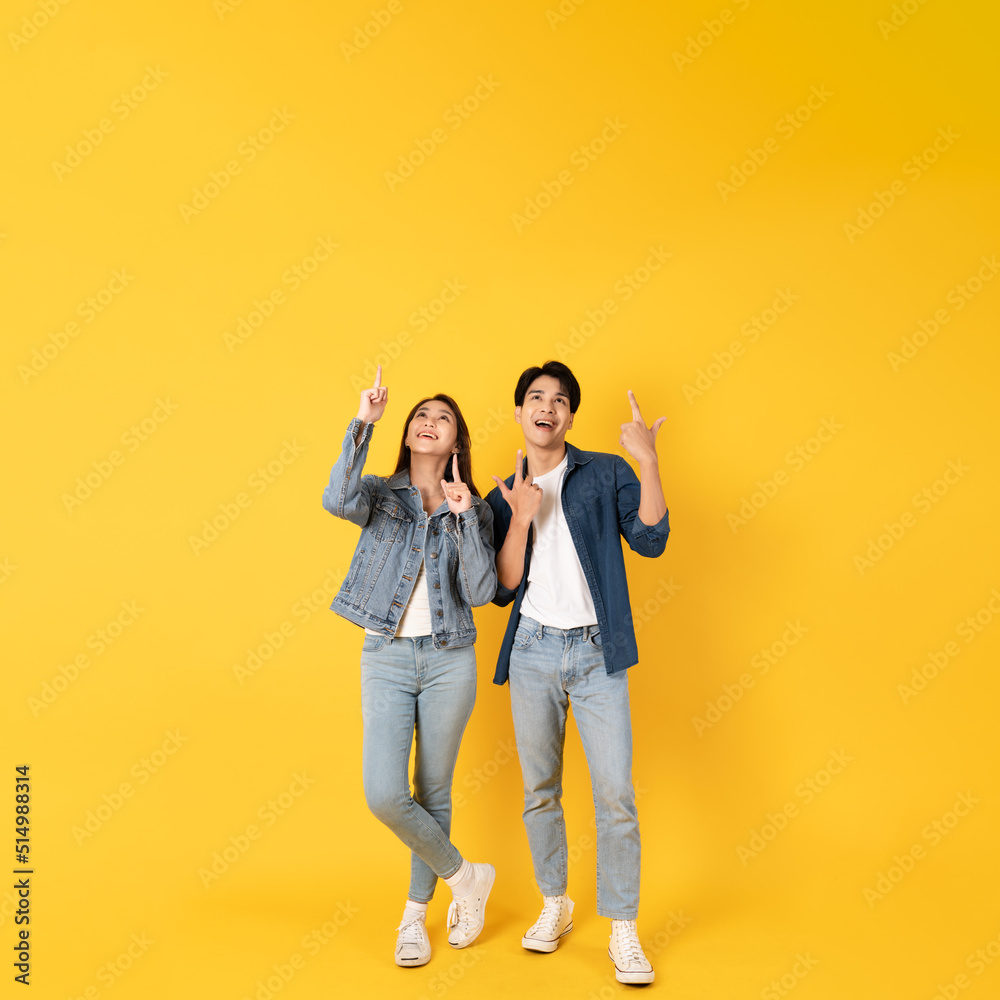 Two Young good looking asian couple using isolated on yellow background presenting to copy space feeling excited Two Young good looking asian couple using isolated on yellow background presenting to copy space feeling excited