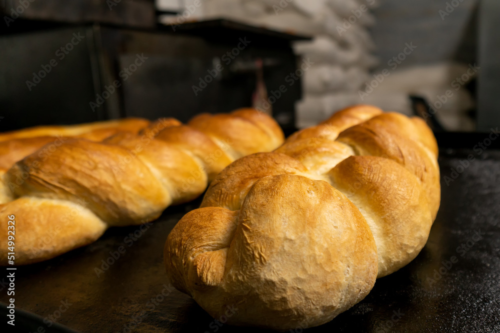 Close-up of a bun or bakery product in the form of a pigtail on a baking sheet from the oven. Fresh pastries