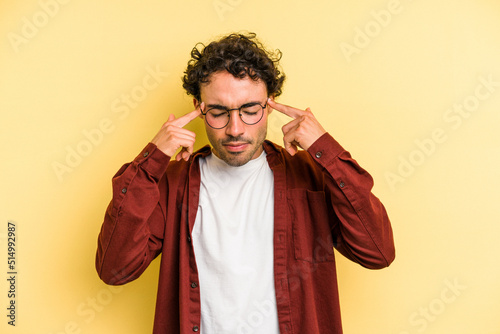 Young caucasian man isolated on yellow background focused on a task, keeping forefingers pointing head.