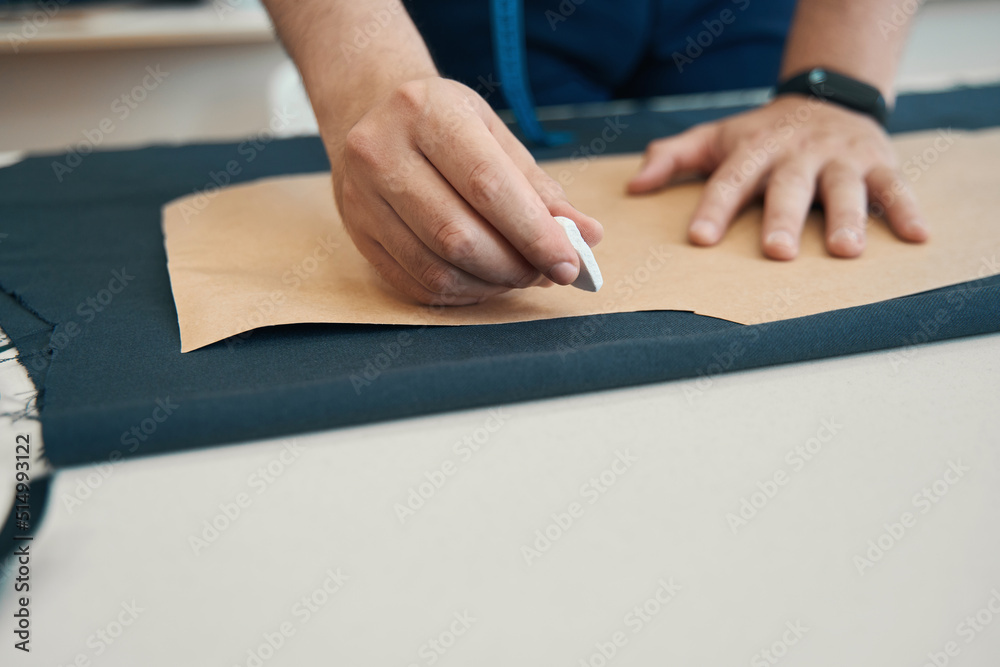 Pattern lies on piece of dark fabric and is pressed by hand Pattern lies on piece of dark fabric and is pressed by hand
