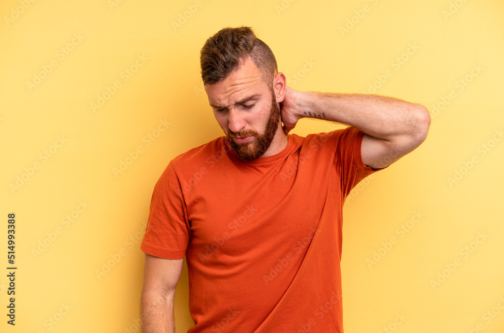 Young caucasian man isolated on yellow background suffering neck pain due to sedentary lifestyle. Young caucasian man isolated on yellow background suffering neck pain due to sedentary lifestyle.