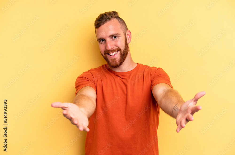 Young caucasian man isolated on yellow background showing a welcome expression. Young caucasian man isolated on yellow background showing a welcome expression.