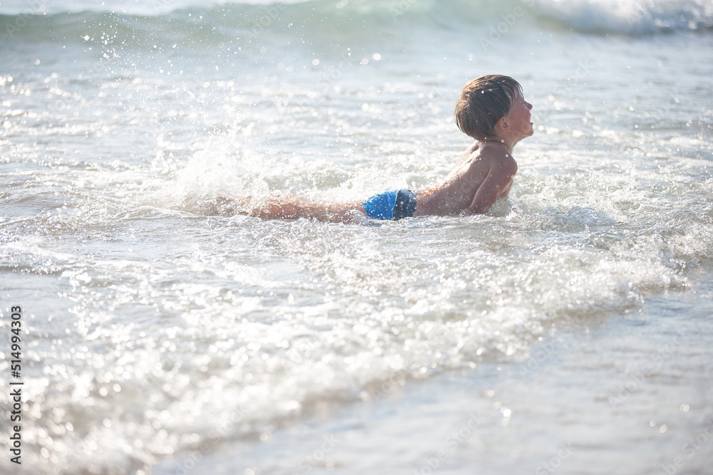 A little boy on the beach, playing with the waves, summer time. Concept of relaxation and a healthy lifestyle A little boy on the beach, playing with the waves, summer time. Concept of relaxation and a healthy lifestyle