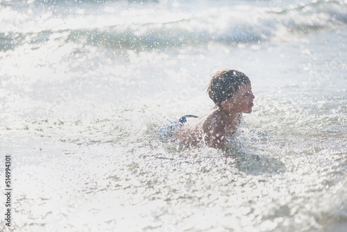 A little boy on the beach, playing with the waves, summer time. Concept of relaxation and a healthy lifestyle