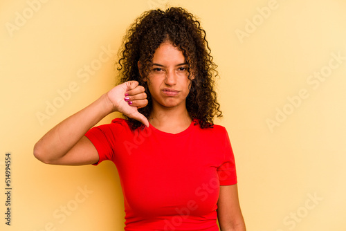 Young Brazilian woman isolated on yellow background showing thumb down, disappointment concept.