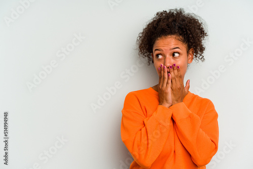Young Brazilian woman isolated on blue background thoughtful looking to a copy space covering mouth with hand.