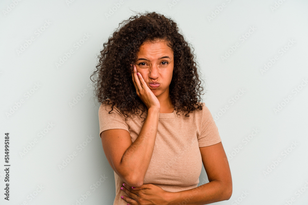Young Brazilian woman isolated on blue background blows cheeks, has tired expression. Facial expression concept.