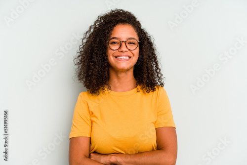 Young Brazilian woman isolated on blue background who feels confident, crossing arms with determination. photo