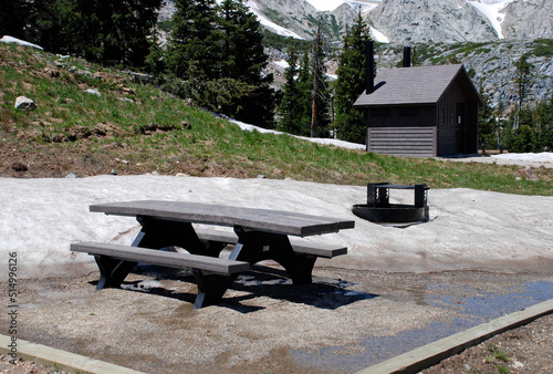 A picnic table near some remanent snow banks  photo