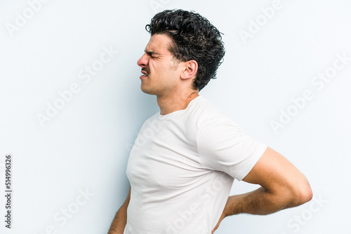 Young caucasian man isolated on blue background suffering a back pain. © Asier