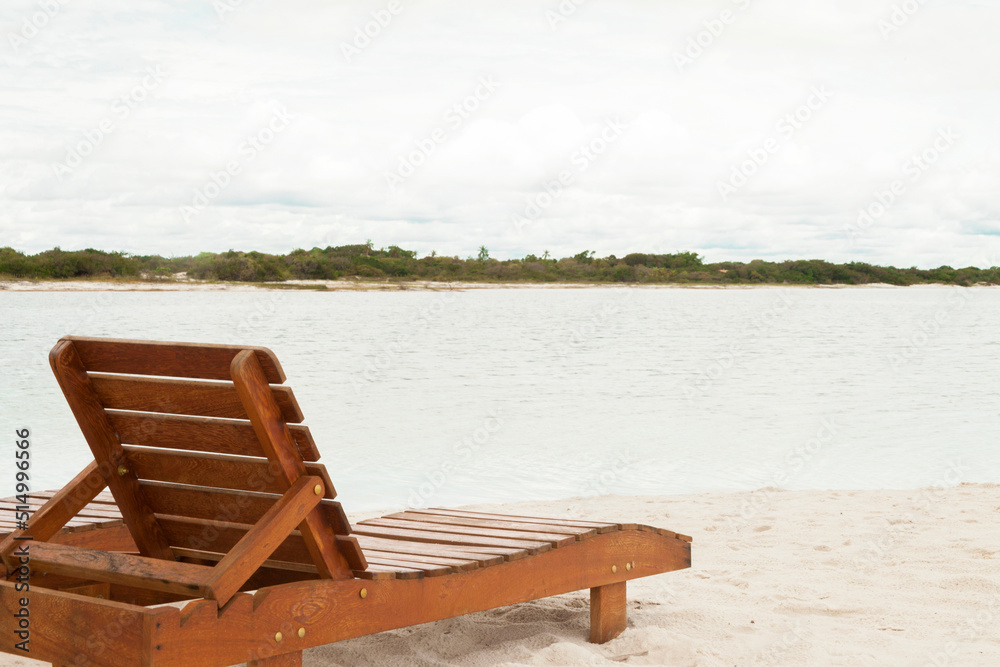 Fototapeta premium Deckchair lounger on the edge of the beach in summer with nice tropical weather. Resort by the sea in Brazil. Beach chair concept. Tourism concept. Copy space.