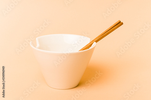 White noddles bowl with chopstick isolated on beige background