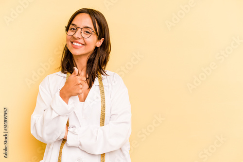 Young nutritionist hispanic woman isolated on yellow background smiling and raising thumb up photo