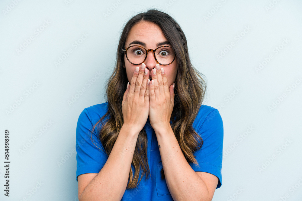 Young caucasian woman isolated on blue background shocked, covering mouth with hands, anxious to discover something new. Young caucasian woman isolated on blue background shocked, covering mouth with hands, anxious to discover something new.