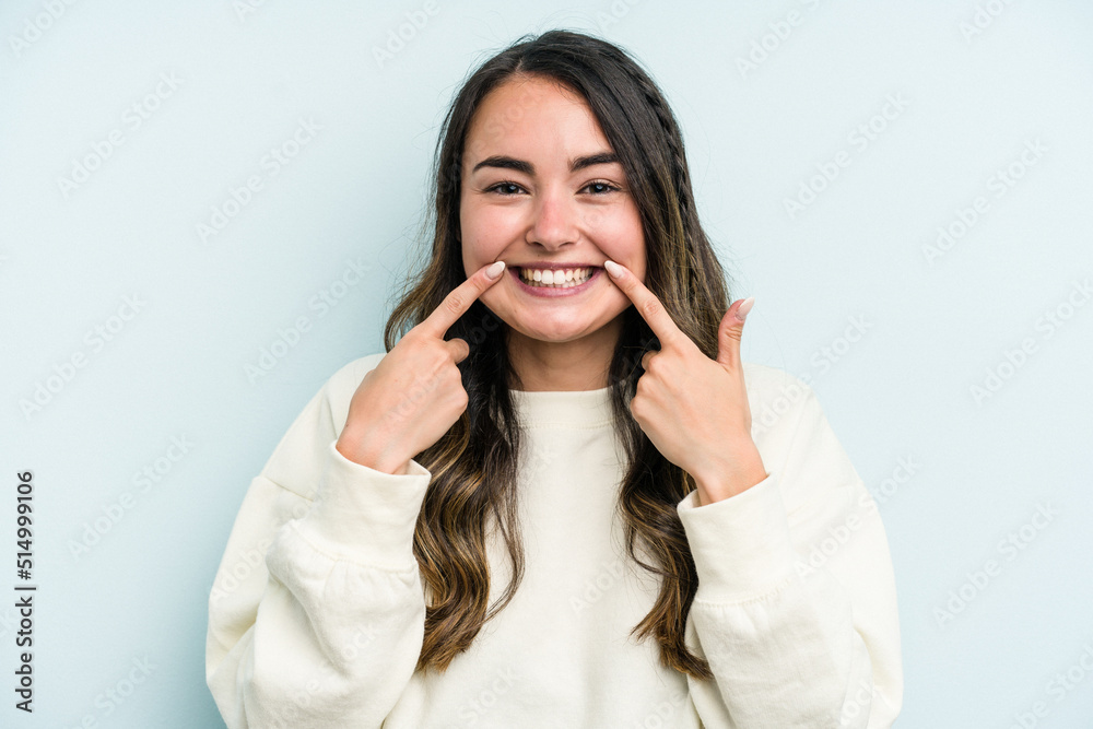Young caucasian woman isolated on blue background smiles, pointing fingers at mouth. Young caucasian woman isolated on blue background smiles, pointing fingers at mouth.