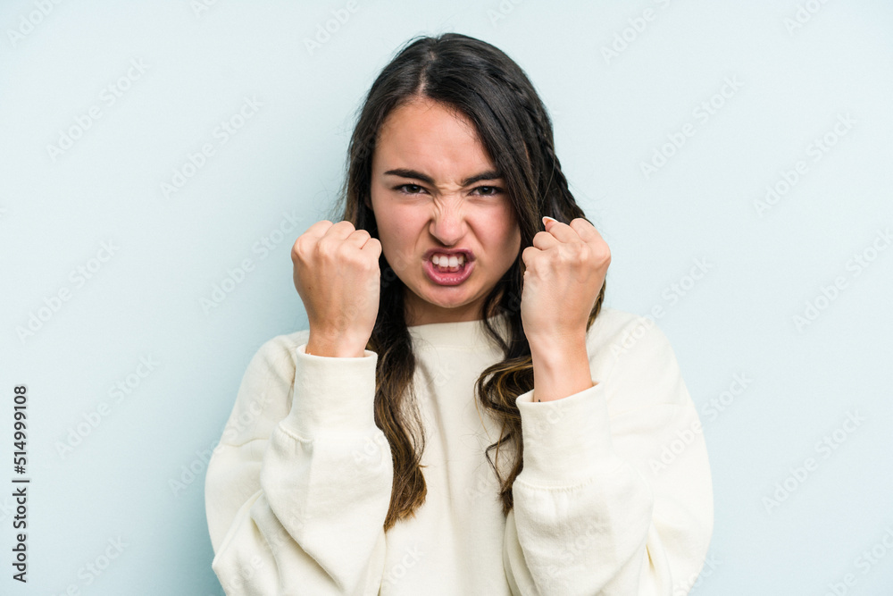 Young caucasian woman isolated on blue background upset screaming with tense hands. Young caucasian woman isolated on blue background upset screaming with tense hands.