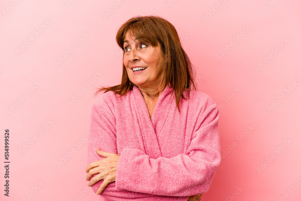Middle age caucasian woman wearing a bathrobe isolated on pink background looks aside smiling, cheerful and pleasant. Middle age caucasian woman wearing a bathrobe isolated on pink background looks aside smiling, cheerful and pleasant.