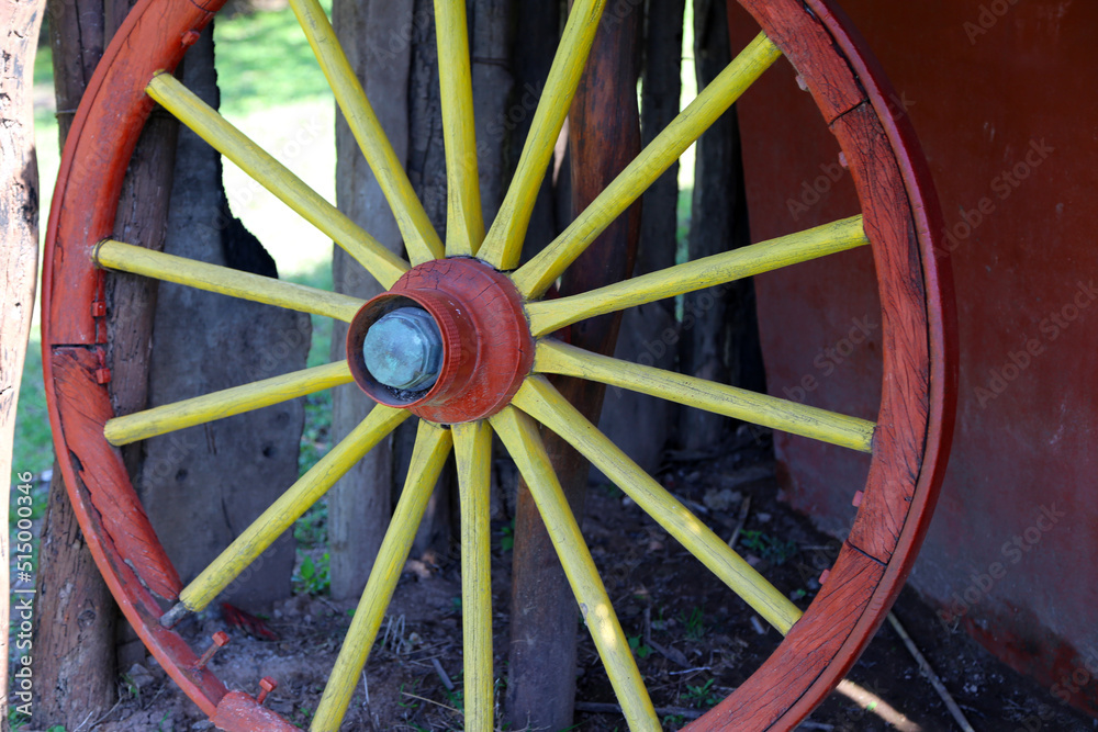 
Old cart wheel. Wooden wheel of old cart. Ancient wheel. Field work tool. Colorful wheel used as a decorative element.