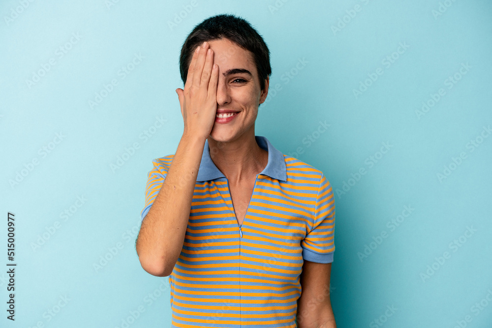 Young caucasian woman isolated on blue background having fun covering half of face with palm. Young caucasian woman isolated on blue background having fun covering half of face with palm.